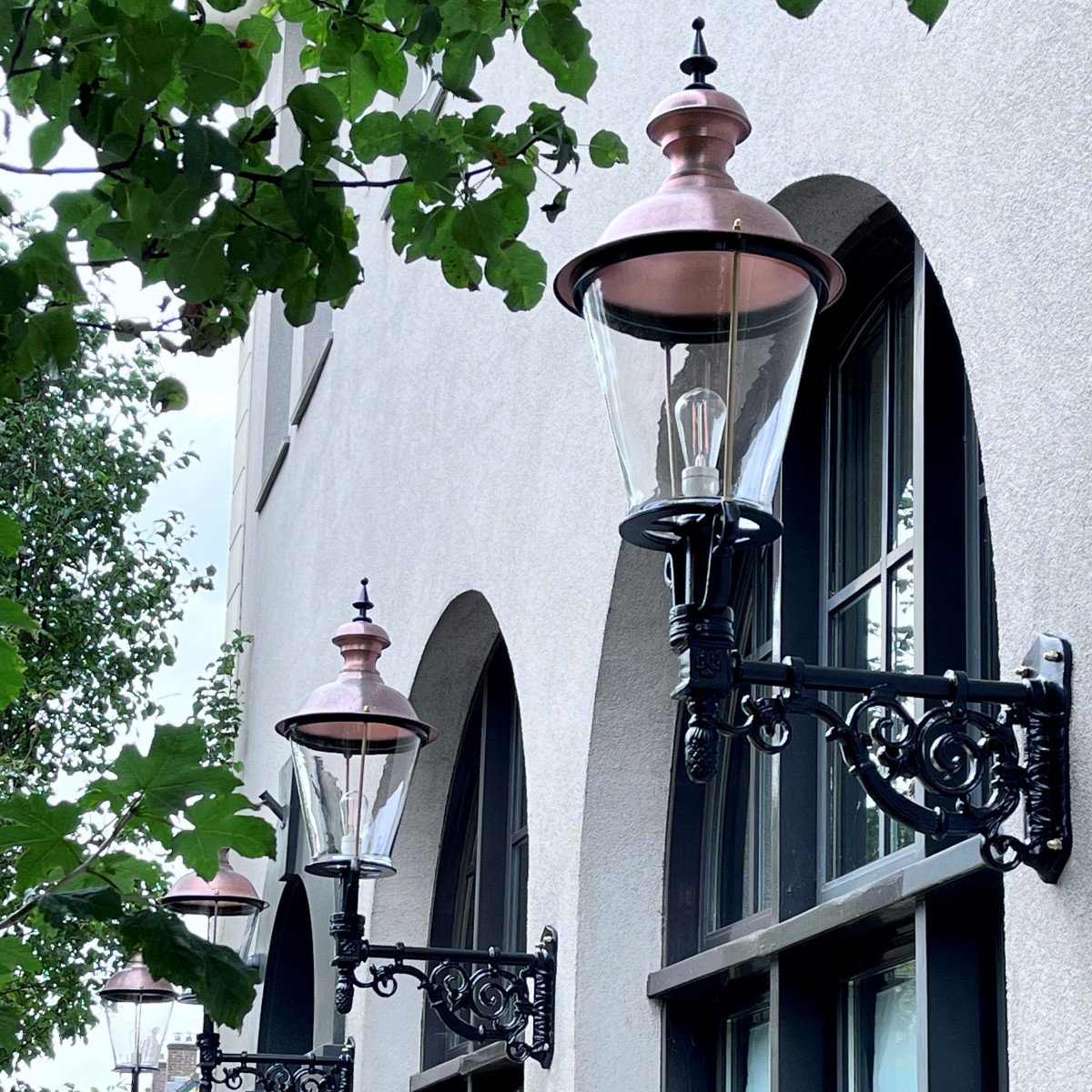 Buitenlamp Amsterdam met koperen deksel en sierlijke zwarte wandarm