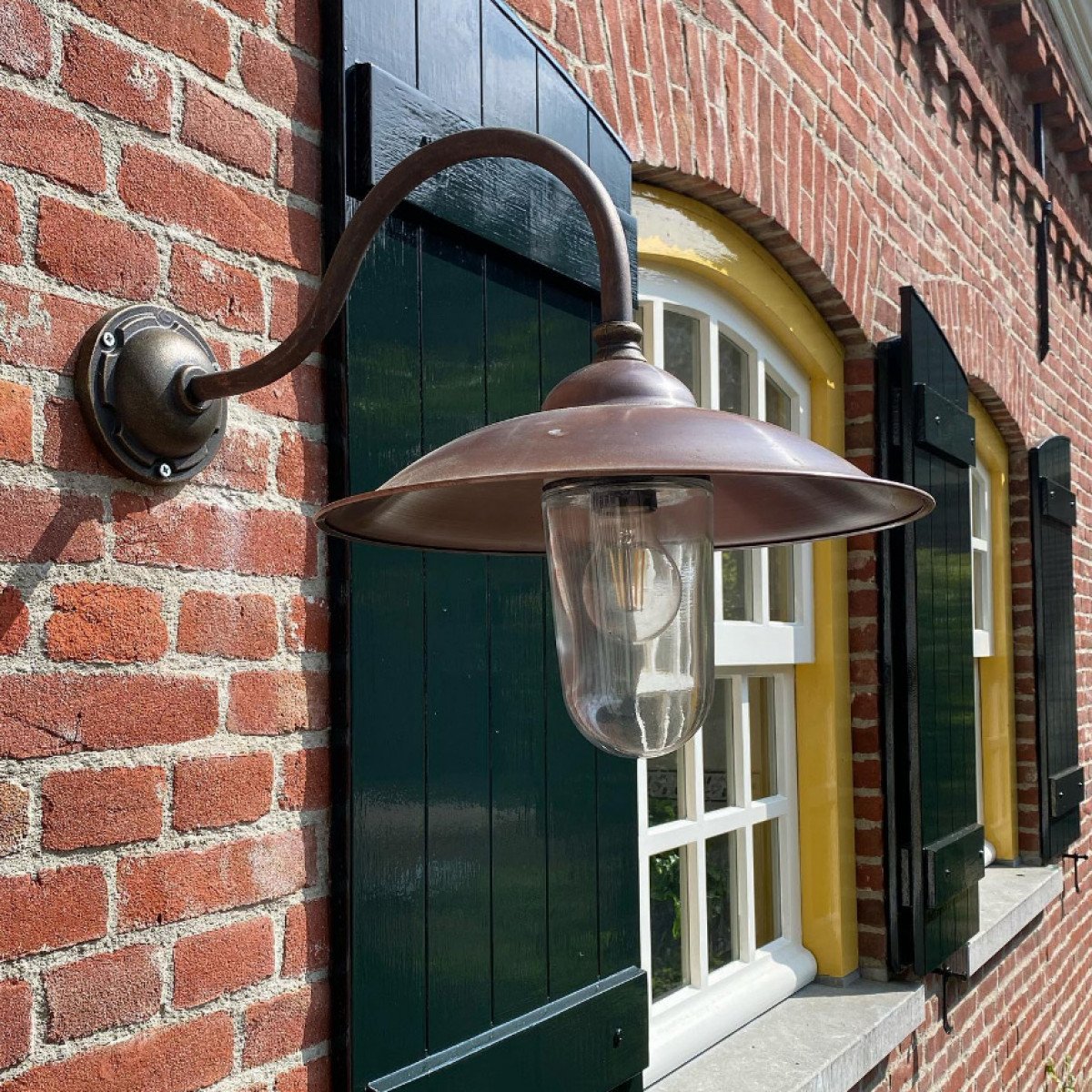 Vienna I stallamp met bronzen wandarm en koperen kap, klassieke buitenlamp met neerwaartse lichtval, helder glazen stolp