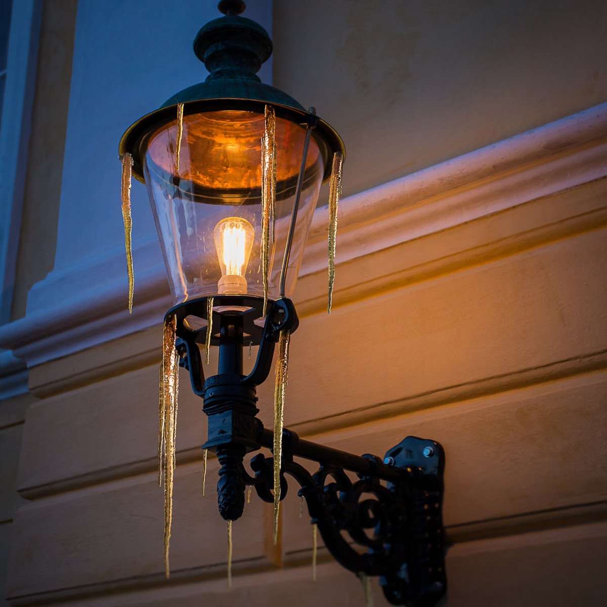 Buitenlamp Amsterdam met koperen deksel en sierlijke zwarte wandarm