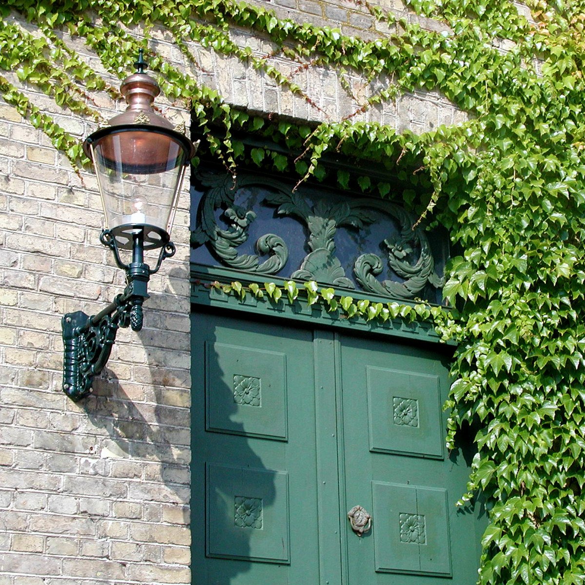 Buitenlamp Amsterdam met koperen deksel en sierlijke zwarte wandarm
