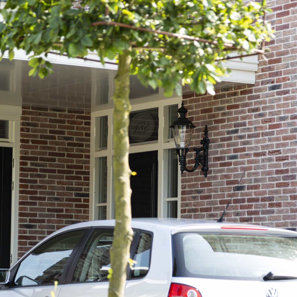 Muurlamp Odense L met koperen deksel, zwarte wandarm en helder kunststof glas