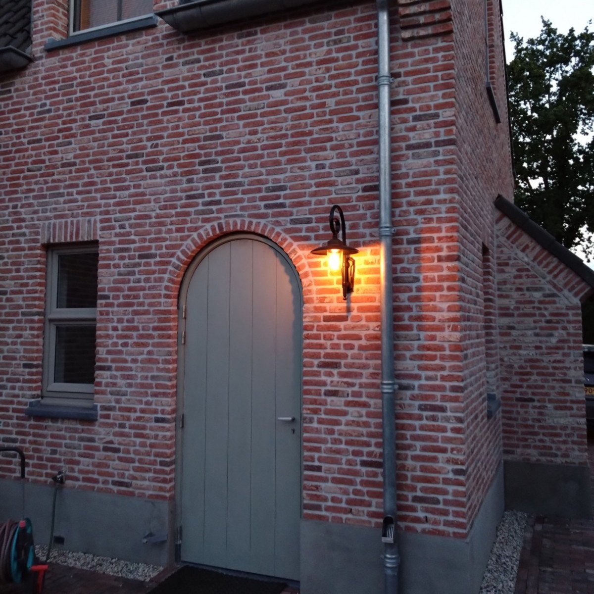 Buitenlamp Orly met sierlijke krularm, zwarte aluminium kap, bronzen flens en glazen stolp,  Wandlamp in Franse stijl.