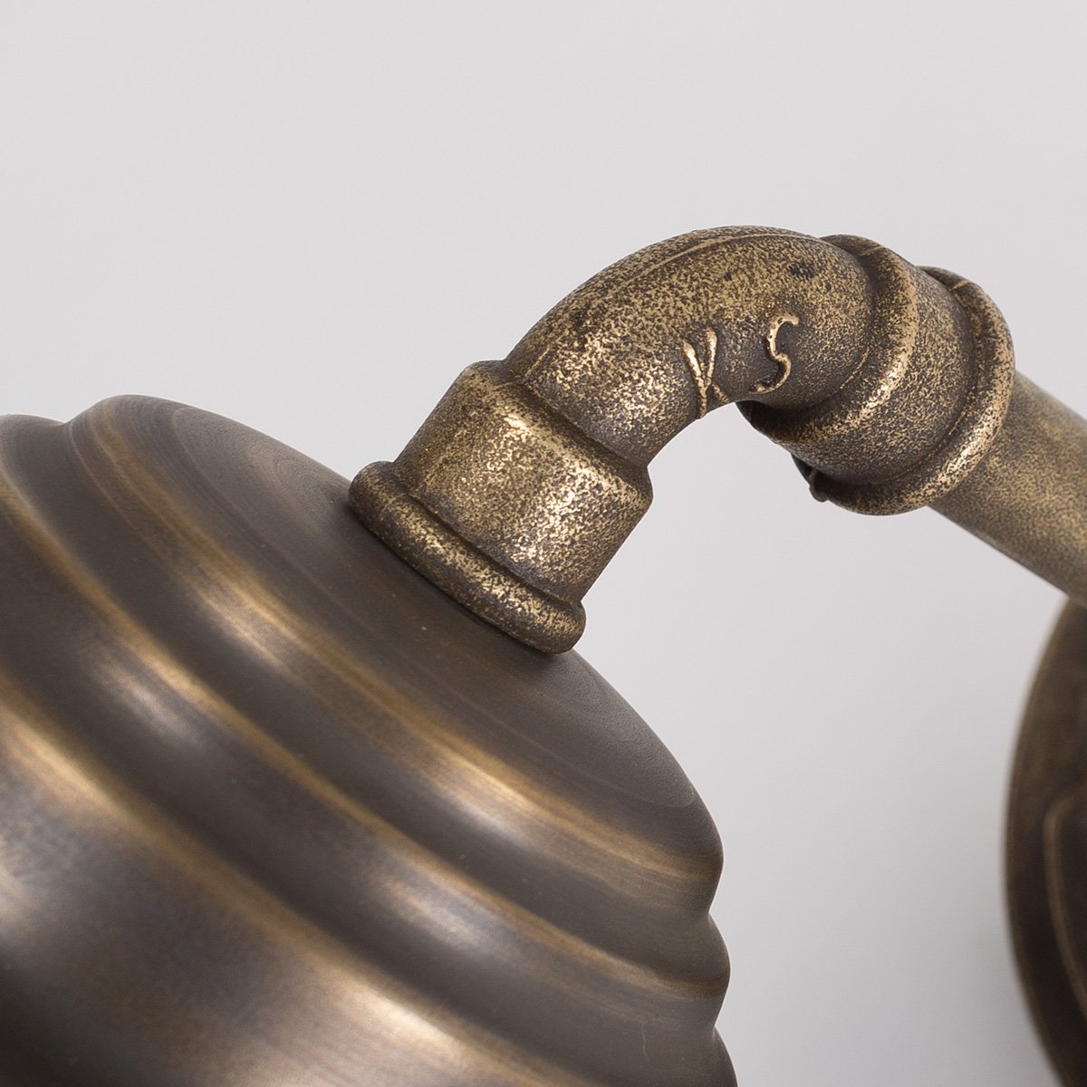 Buitenlamp Tour met bronzen wandarm, koperen kap, helder stolpglas en beschermend raster.