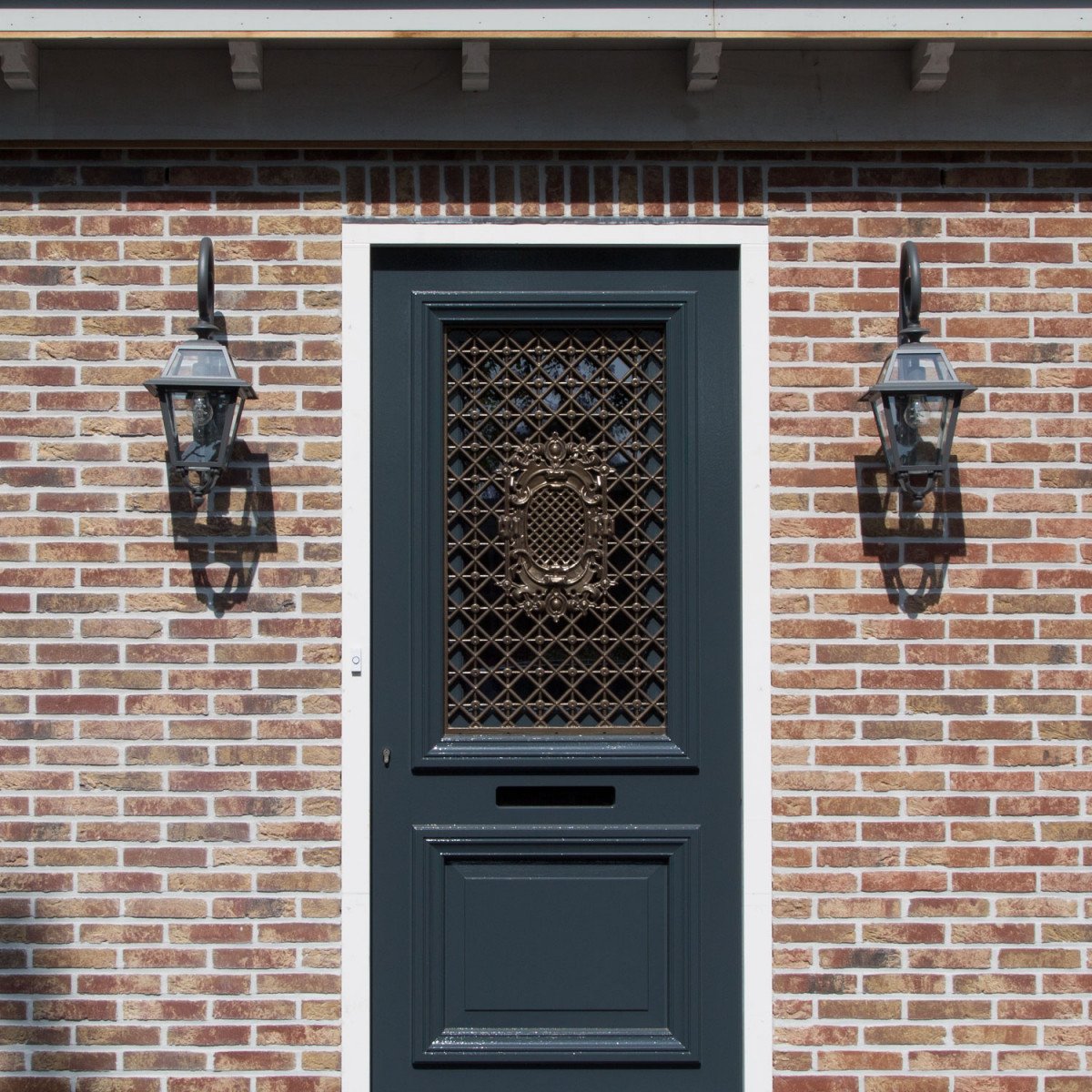 Klassieke buitenlamp Amstelrade met sierlijke krularm, heldere beglazing en poedercoating in zwart of antraciet.