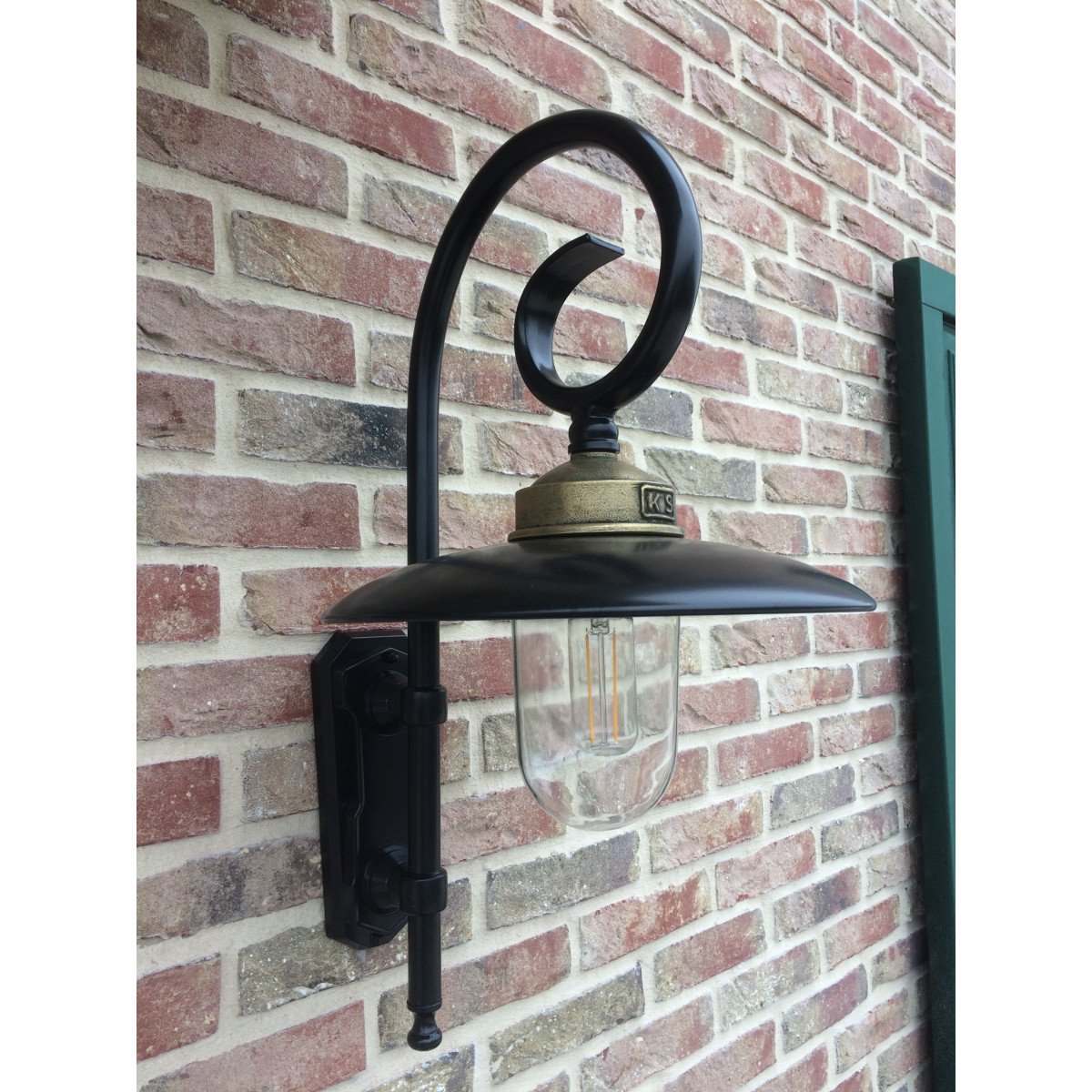 Buitenlamp Orly met sierlijke krularm, zwarte aluminium kap, bronzen flens en glazen stolp,  Wandlamp in Franse stijl.